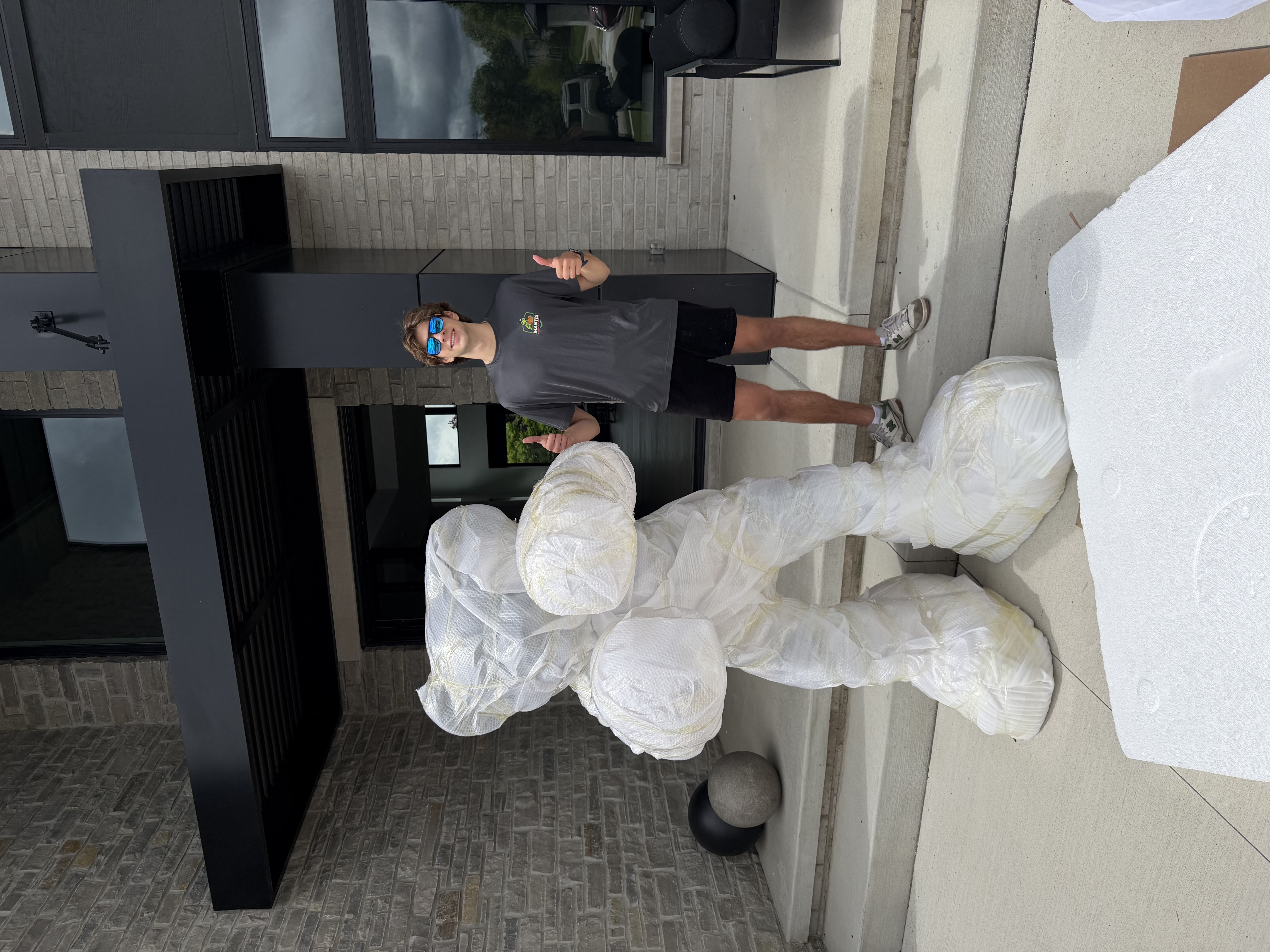 Mantis Moving crew member giving a thumbs up beside a large sculpture wrapped in moving blankets